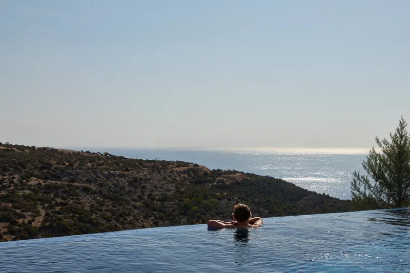 Swimmer at an infinity pool edge looking out to the sea