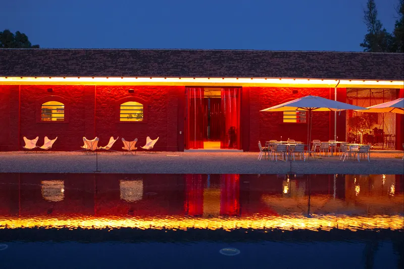 Red buildings reflected in the pool at dusk with lit windows