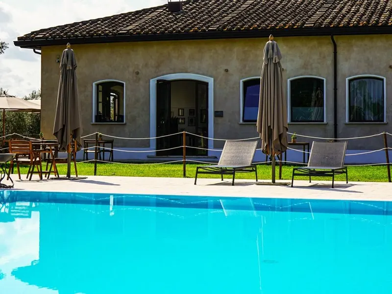 Pool with loungers and umbrellas in front of the estate building