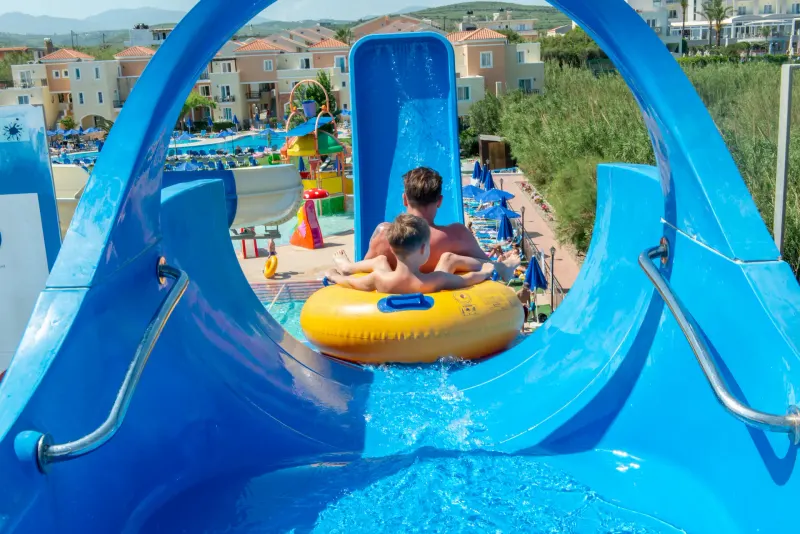 Family riding a ring down a blue water slide