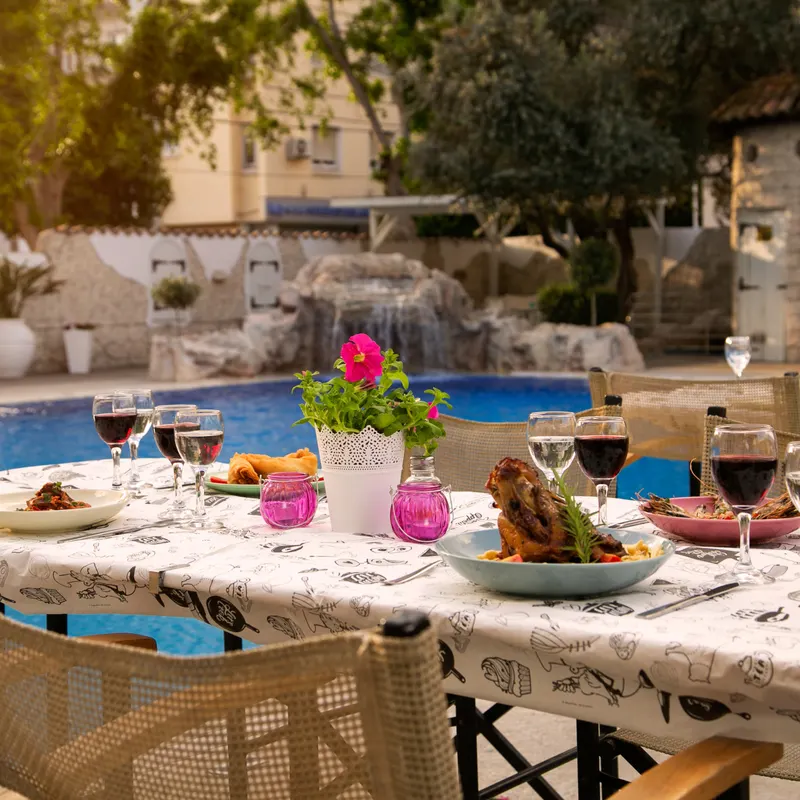 Poolside dining table set beside the pool and waterfall