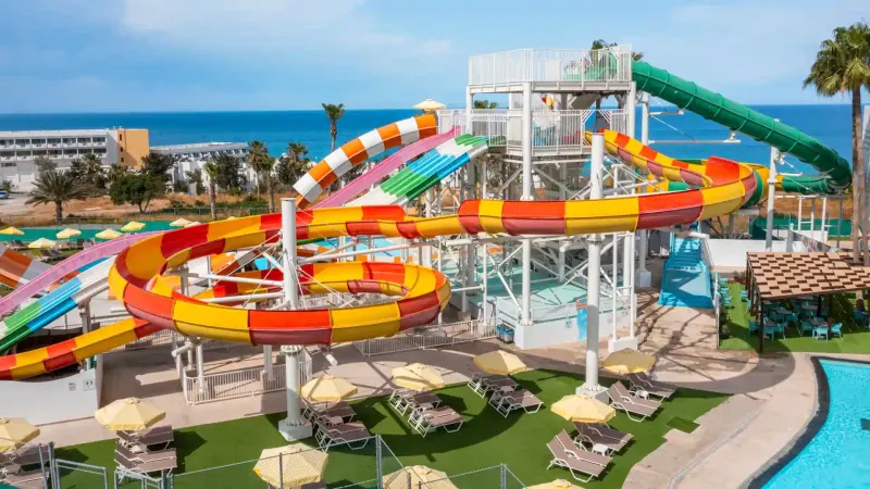 Spiral slides over a lawn with sunbeds and umbrellas