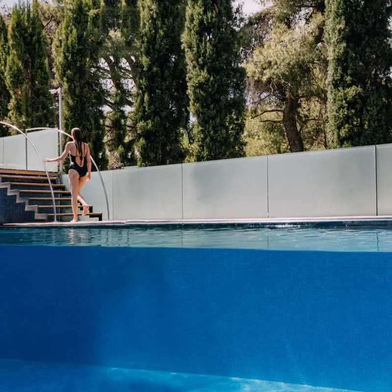 Glass-walled pool with steps and cypress trees
