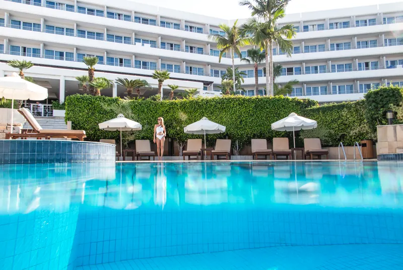 Outdoor pool with sunbeds and umbrellas in front of the hotel