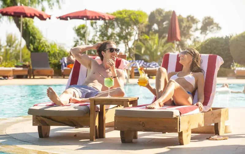 Couple on striped sunloungers beside the pool
