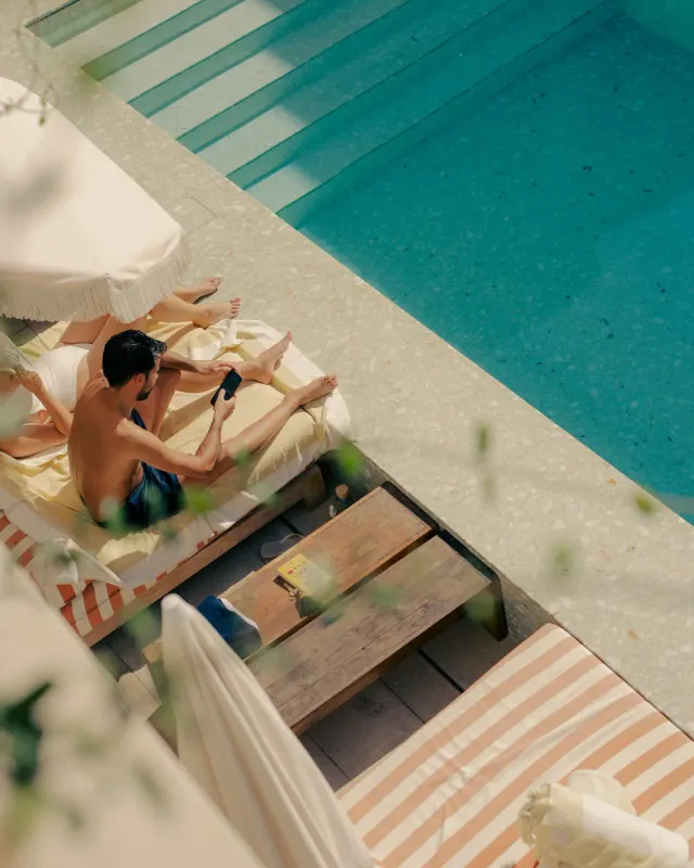 Overhead view of a guest on a striped sunbed next to the pool